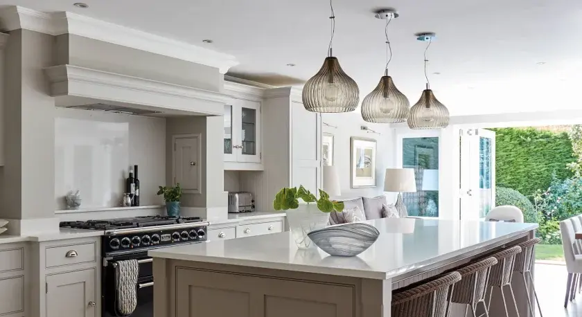 Elegant kitchen with island, dining area, and garden view. Showcasing latest kitchen designs with neutral tones and modern lighting.
