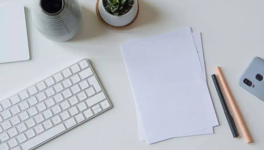 Schreibtisch mit Tastatur, Notizen, Stiften und Handy. Perfekt, um das Fernstudium zu organisieren und den Überblick zu behalten.