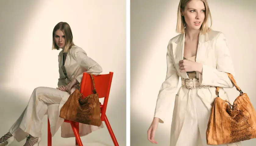 Modelo luce un traje beige y un bolso de cuero marrón con detalles calados.