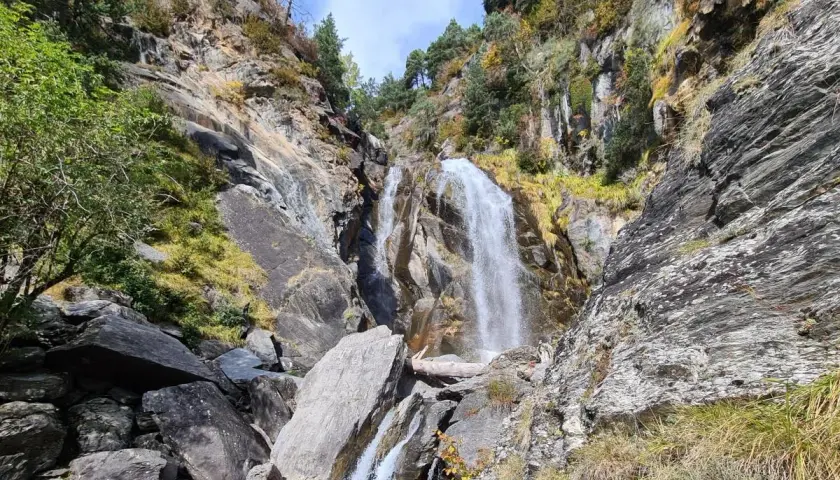 Cascada imponente en la ruta Rupit, rodeada de rocas y vegetación otoñal. El agua cae con fuerza sobre las piedras, creando un paisaje natural espectacular.