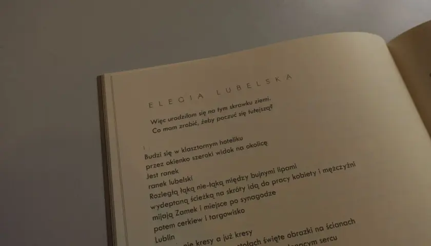 Otwarta książka z tekstem wiersza "Elegia Lubelska" Julii Hartwig.