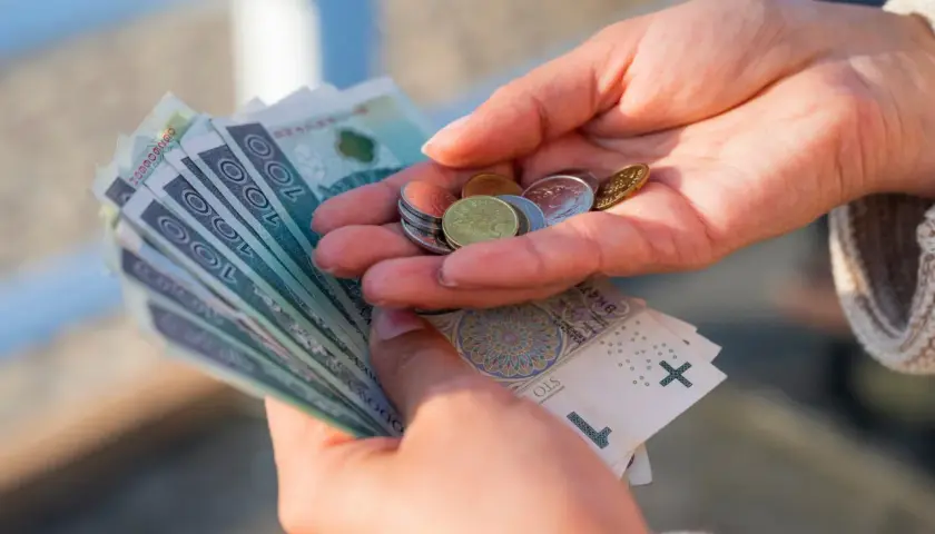 Dłonie liczą banknoty i monety. Czy to wystarczy na życie, gdy placa minimalna netto 2026 będzie obowiązywać?