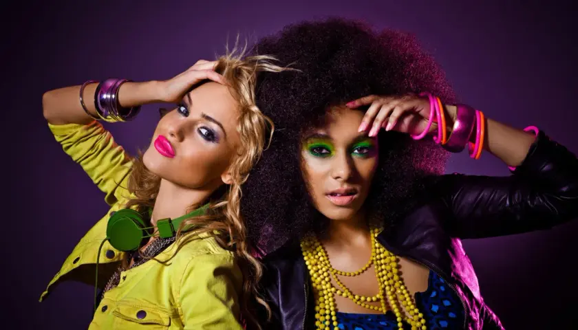 Dwie kobiety w stylu lat 80. na imprezie: neonowe kolory, afro i mocny makijaż.