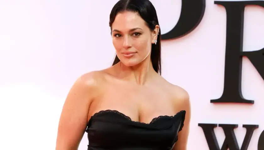 Ashley Graham posa con un vestido negro sin tirantes, luciendo elegante y segura.