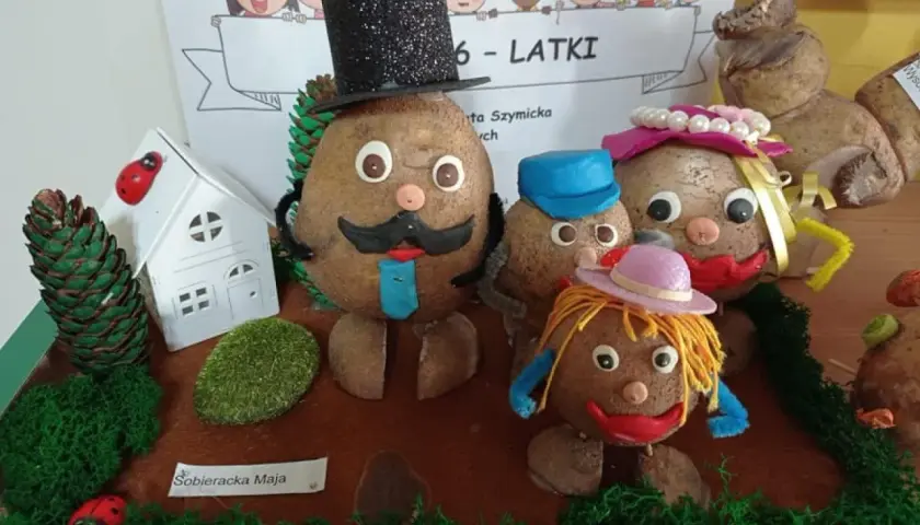 Figurki z ziemniaków przedstawiające rodzinę, ubrane w kapelusze i ubrania, na tle rysunku dzieci.