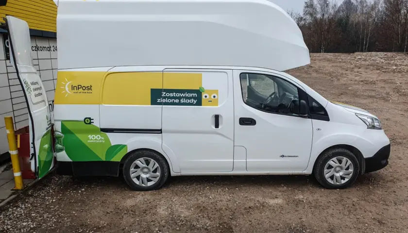 Biały Nissan e-NV200 InPost z hasłem "Zostawiam zielone ślady" i grafiką liścia.