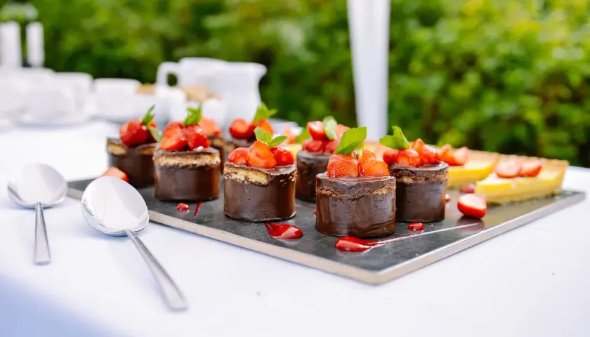 Catering przerwa kawowa: czekoladowe mini torty z truskawkami i cytrynowa tarta na eleganckim talerzu.
