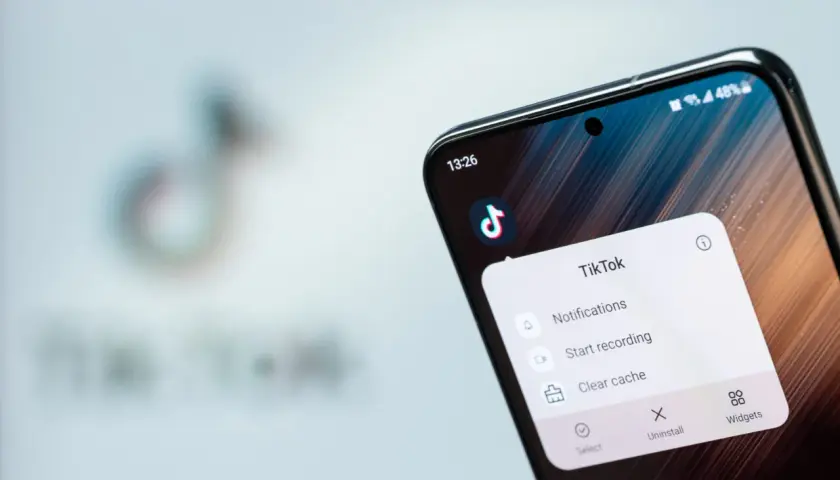 Telefon z aplikacją TikTok, gdzie widać opcję "Clear cache" (wyczyść pamięć podręczną), by przyspieszyć działanie.