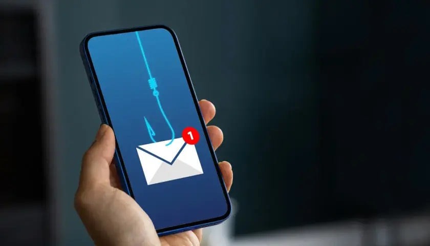 Telefon z ikoną koperty i haczykiem wędkarskim symbolizującym wyłudzenie pieniędzy. Uważaj na podejrzane wiadomości!