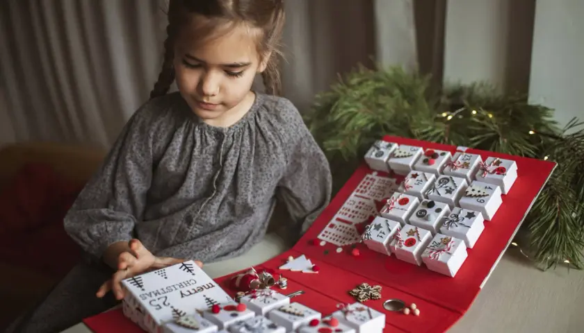 Niña prepara su calendario de adviento, una manualidad navideña para contar los días.