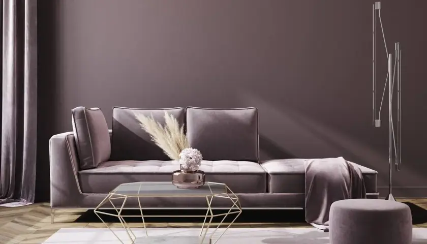 Ein luxuriöses Wohnzimmer in mauve farbe mit einem Samtsofa, einem geometrischen Couchtisch und einem Hocker.