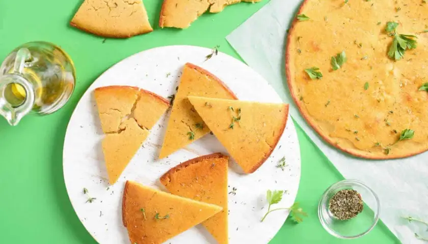 Une délicieuse socca coupée en parts, garnie d'herbes fraîches. Parfait pour une recette facile et savoureuse.