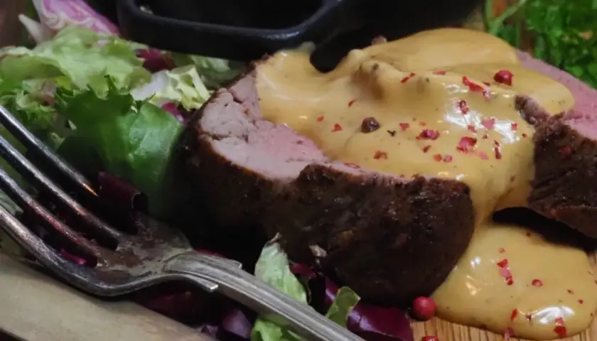 Saftig oxfilé med en krämig sås, garnerad med rosa pepparkorn. Serveras med sallad och potatis.