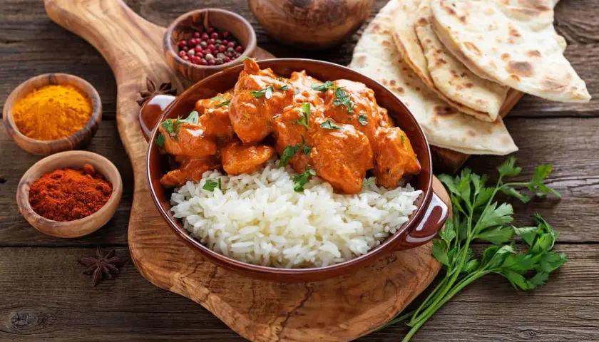 Aksamitny kurczak tikka masala z ryżem basmati, podany z plackami naan i aromatycznymi przyprawami.
