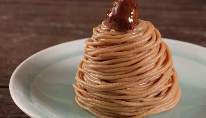 Un delizioso montblanc dolce, un dolce di castagne a forma di cono, guarnito con una castagna lucida.