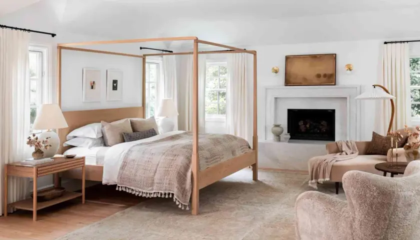 A cozy bedroom with a four-poster bed, fireplace, and plush seating, perfect for romance in bed.