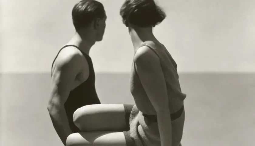Pareja en trajes de baño, capturada por Patrick Demarchelier, mira hacia el mar.