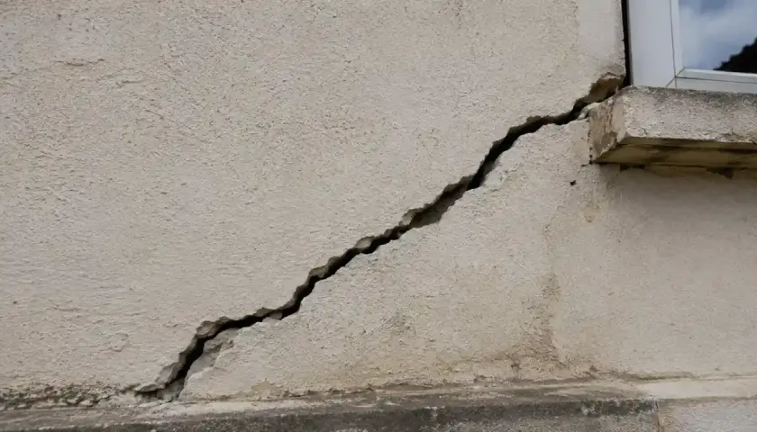 Une fissure importante traverse la façade d'un bâtiment, nécessitant une réparation urgente.