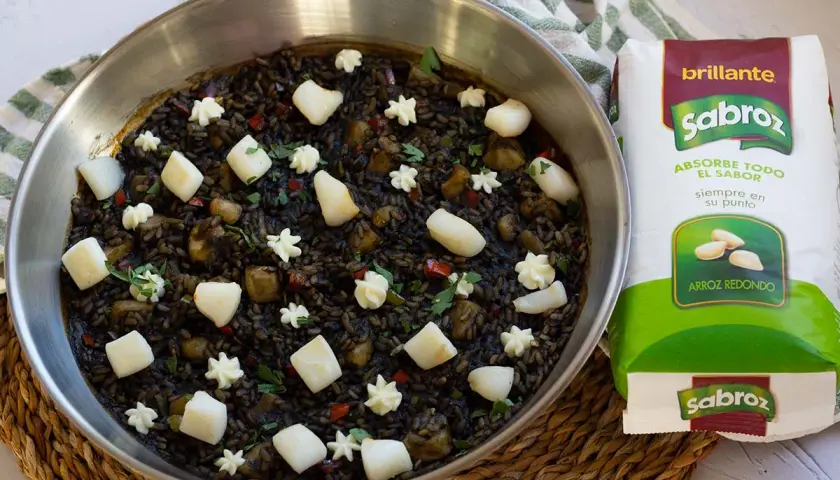 Arroz negro con sepia, adornado con trozos de sepia y puntos de alioli, listo para ser cocinado con arroz redondo Sabroz.