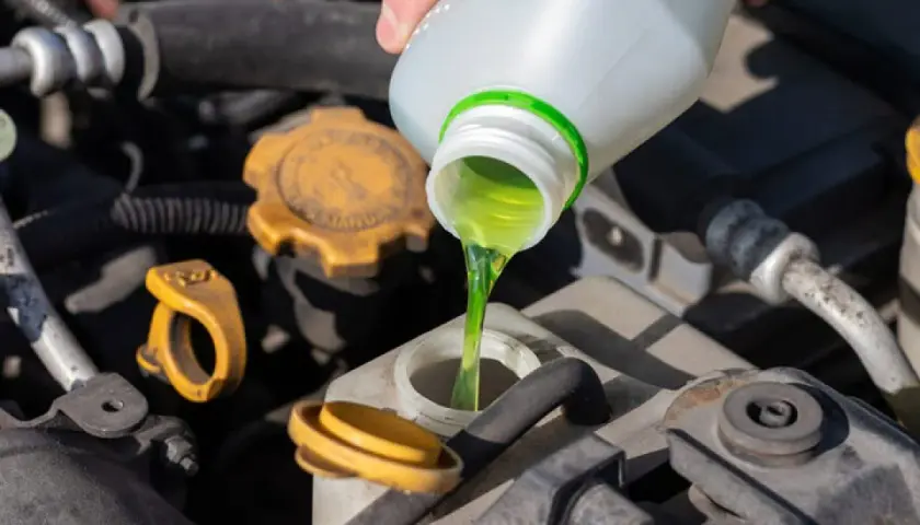 Se vierte líquido verde brillante en el depósito del coche. Esto demuestra para qué sirve el anticongelante del coche: mantener el motor a la temperatura adecuada.