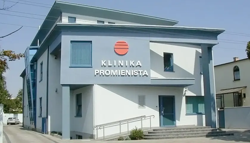 Nowoczesny budynek kliniki "Promienista" w Poznaniu z niebieskimi elementami i logo.