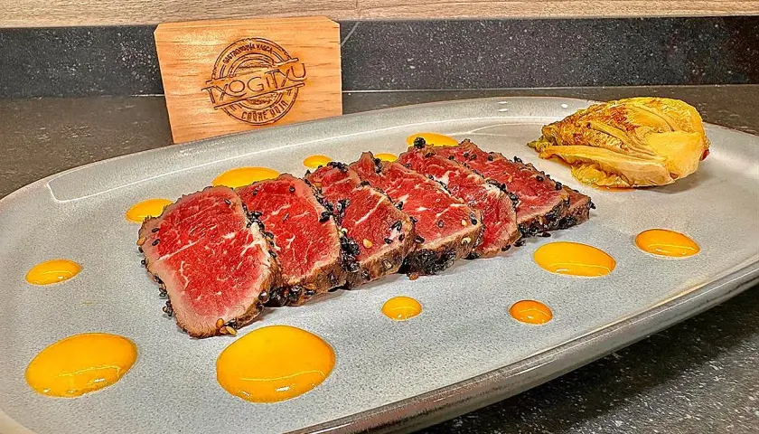Tataki de ternera con costra de sésamo negro, acompañado de un toque de kimchi y salsa amarilla.
