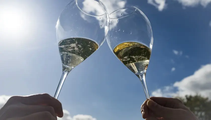 Deux flûtes de champagne pétillant levées en l'air, sous un ciel bleu éclatant. Un toast à Épernay !
