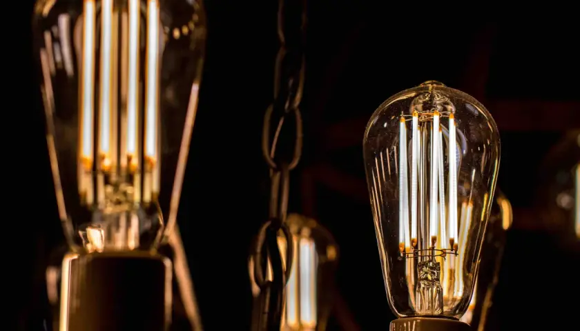 Bombillas led 15w de filamento, con luz cálida, colgadas de cadenas metálicas en la oscuridad.