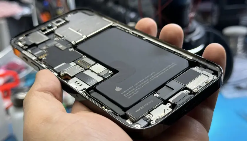 Wnętrze iPhone'a z widoczną baterią i elementami płyty głównej. Czas sprawdz port ładowania USB.