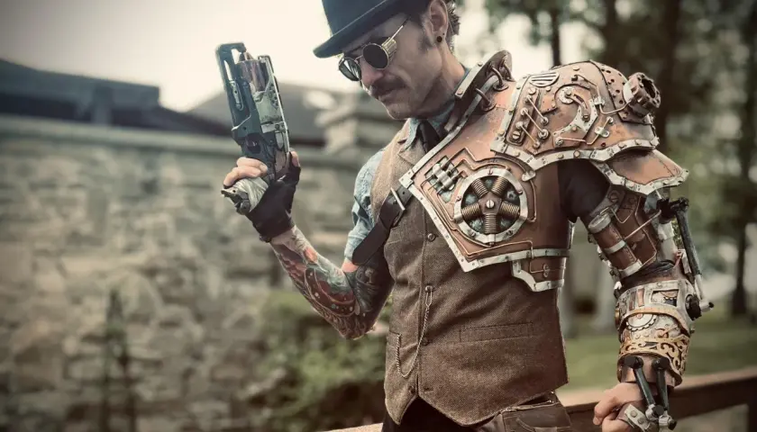 Mężczyzna w stylu steampunk, z cylindrem i goglami, trzyma futurystyczny pistolet. Jego zbroja na ramię i rękę jest pełna mechanicznych detali.