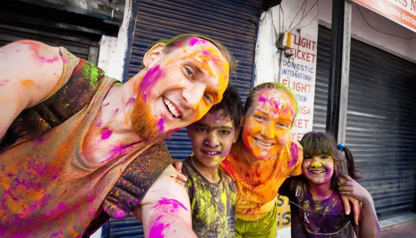 Fröhliche Familie feiert das Holi Festival in Indien, Gesichter und Kleidung bunt mit Pulverfarben bespritzt.