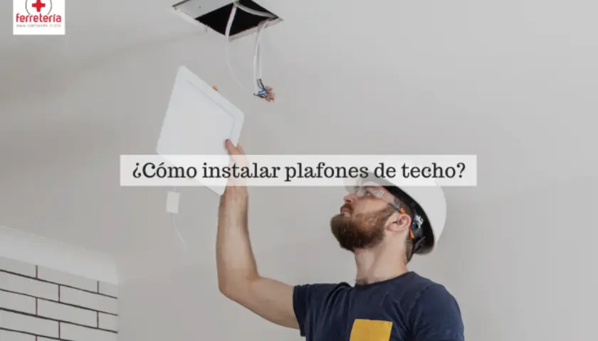 Hombre instalando bombillas plafon de techo, con casco y gafas de seguridad.