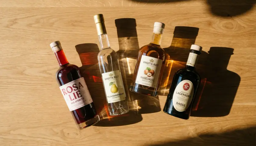 Vier Flaschen mit Spirituosen, darunter ein roter Aperitif, Birnenbrand und Haselnusslikör. Ein polnischer Schnaps könnte hier gut passen.