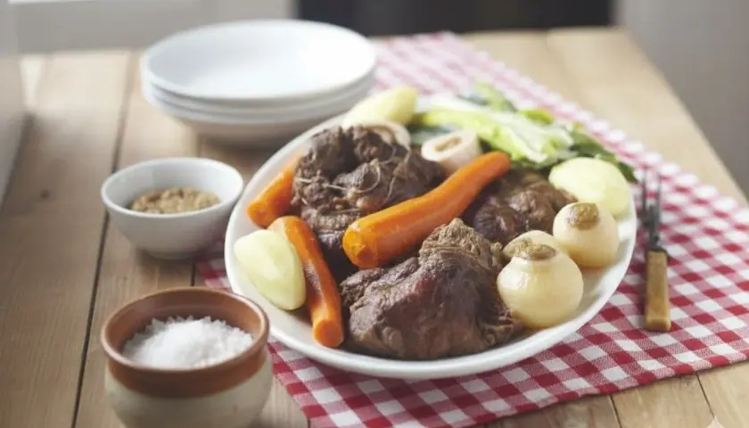 Un plat généreux de pot-au-feu, avec viande, carottes, navets et poireaux, servi avec moutarde et gros sel. Un délice réconfortant, parfait avec un verre de vin blanc.
