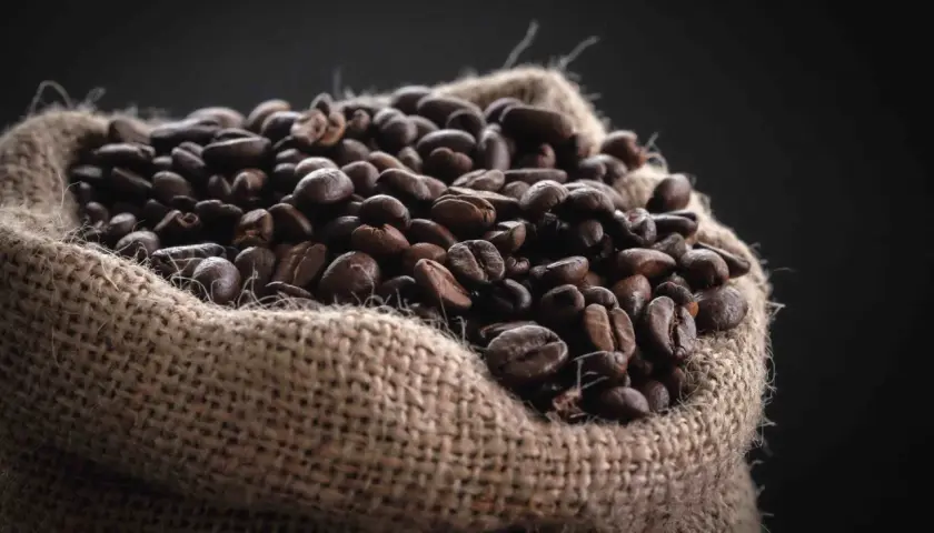 Un saco de arpillera lleno de granos de café tostados, una fuente natural de cafeína para el pelo.