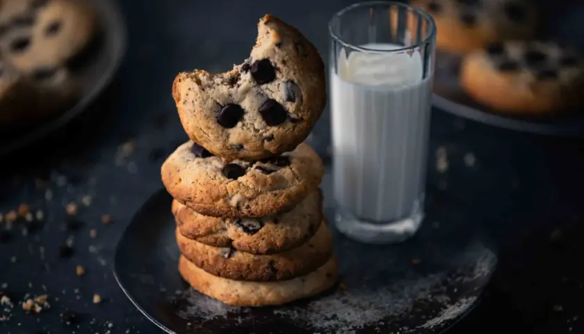 Ein Stapel weicher Chocolate Chip Cookies, perfekt für ein Cookies Rezept. Daneben ein Glas Milch.