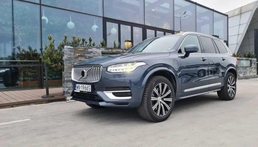 Elegancki, ciemnoszary Volvo XC90 T8 z nowoczesnymi światłami LED stoi przed budynkiem z dużymi, przeszklonymi oknami.
