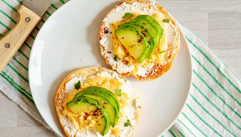 Deux toasts avec fromage frais, œufs brouillés et avocat. Un petit-déjeuner sain et savoureux, idéal pour maîtriser les calories.