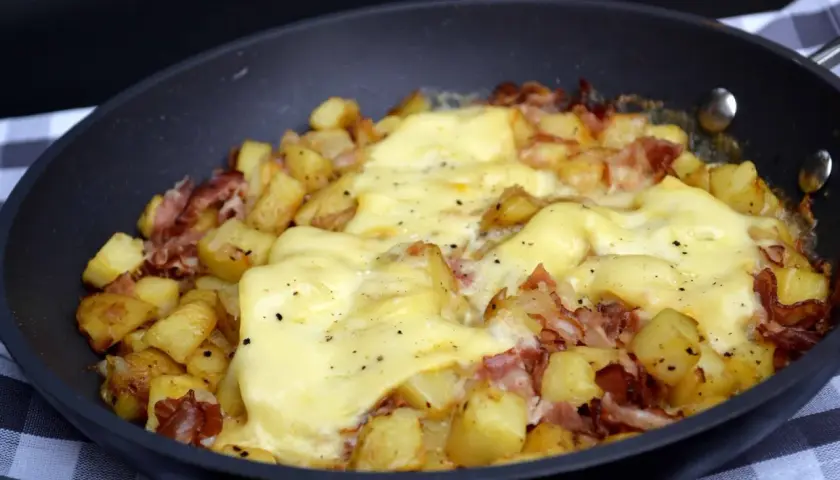 Une poêle de délicieuse pela savoyarde, avec pommes de terre dorées, lardons et fromage fondant. Un plat réconfortant.