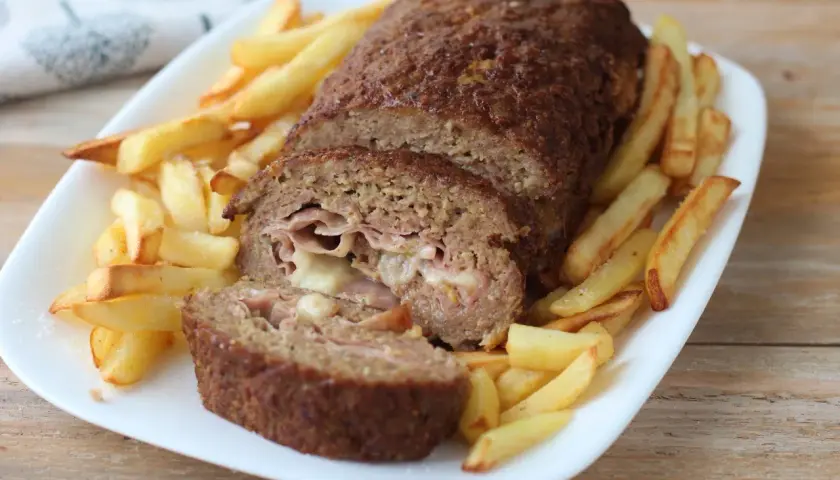 Polpettone ripieno di prosciutto e formaggio, cotto in friggitrice ad aria, servito con patatine fritte croccanti.