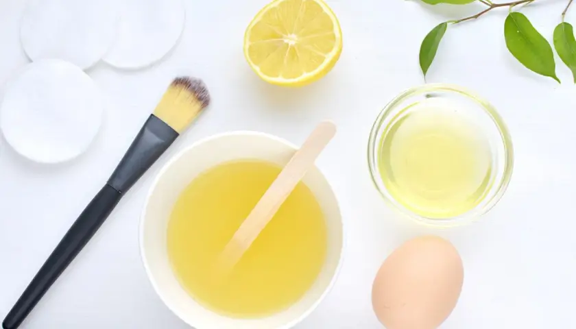 Ingredientes para una mascarilla de huevo para el pelo: huevo, limón, aceite y brocha.