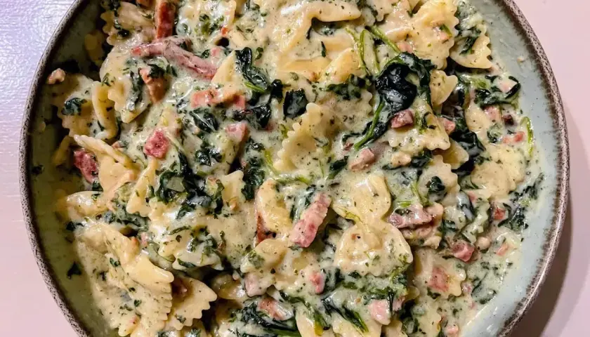 Makaron farfalle w kremowym sosie szpinakowym z kawałkami boczku. Pyszne danie, które zachwyci każdego.