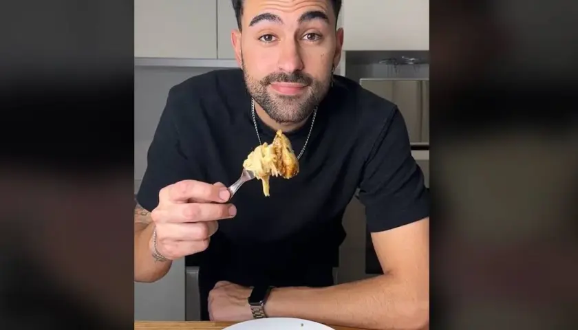 Hombre sonriendo mientras prueba unos deliciosos macarrones con pollo.