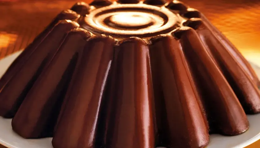 Budino al cioccolato lucido e invitante, con un disegno a spirale al centro e una forma a petali che promette un sapore intenso.