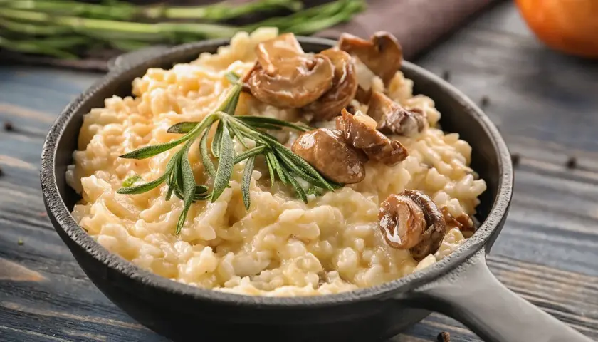 Cremoso arroz italiano con champiñones y romero, servido en sartén de hierro fundido.