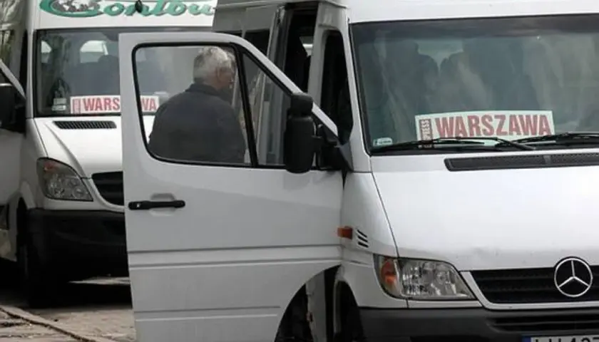 Białe busy Contbus z napisem "WARSZAWA" na przedniej szybie, jeden z otwartymi drzwiami.
