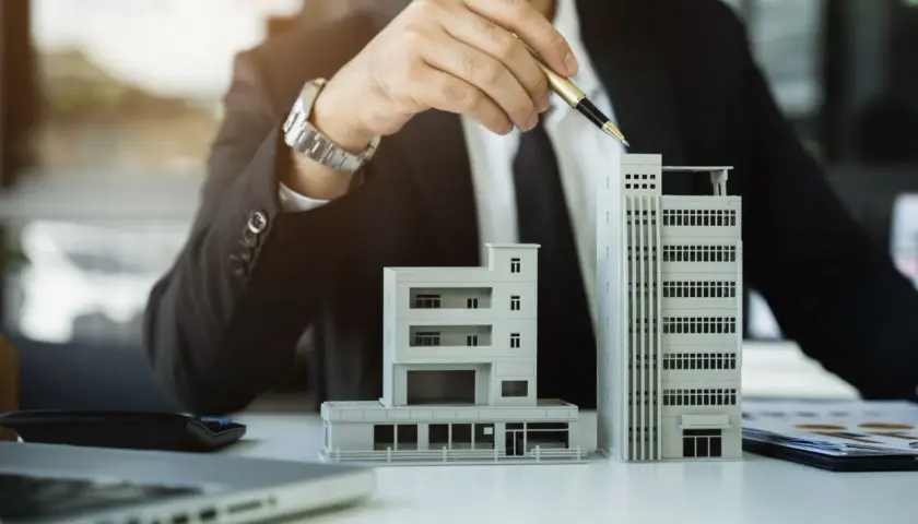 Biznesmen analizuje modele budynków, rozważając umowę na rok i możliwość jej wypowiedzenia.