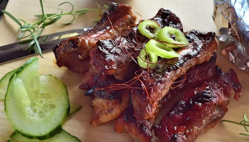 Délicieux ribs barbecue, prêts à déguster. Le temps de cuisson parfait pour des ribs tendres et savoureux. Accompagnés de concombre frais et de romarin.