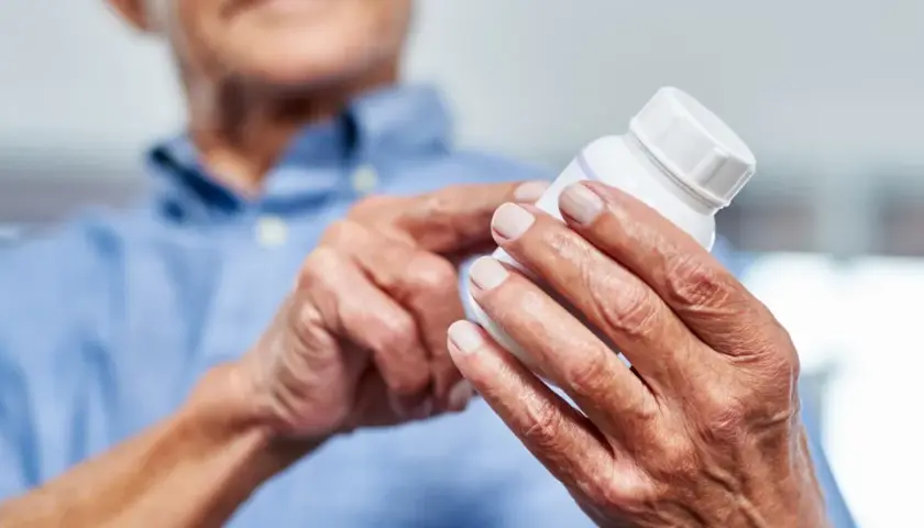 Ältere Hände halten eine Pillendose. Die Glucosamin Wirkung für Gelenke wird hier thematisiert.