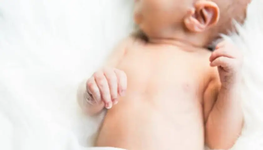 Delikatna skóra niemowlęcia, być może zmagającego się z trądzikiem niemowlęcym lub skazą białkową, na białym tle.
